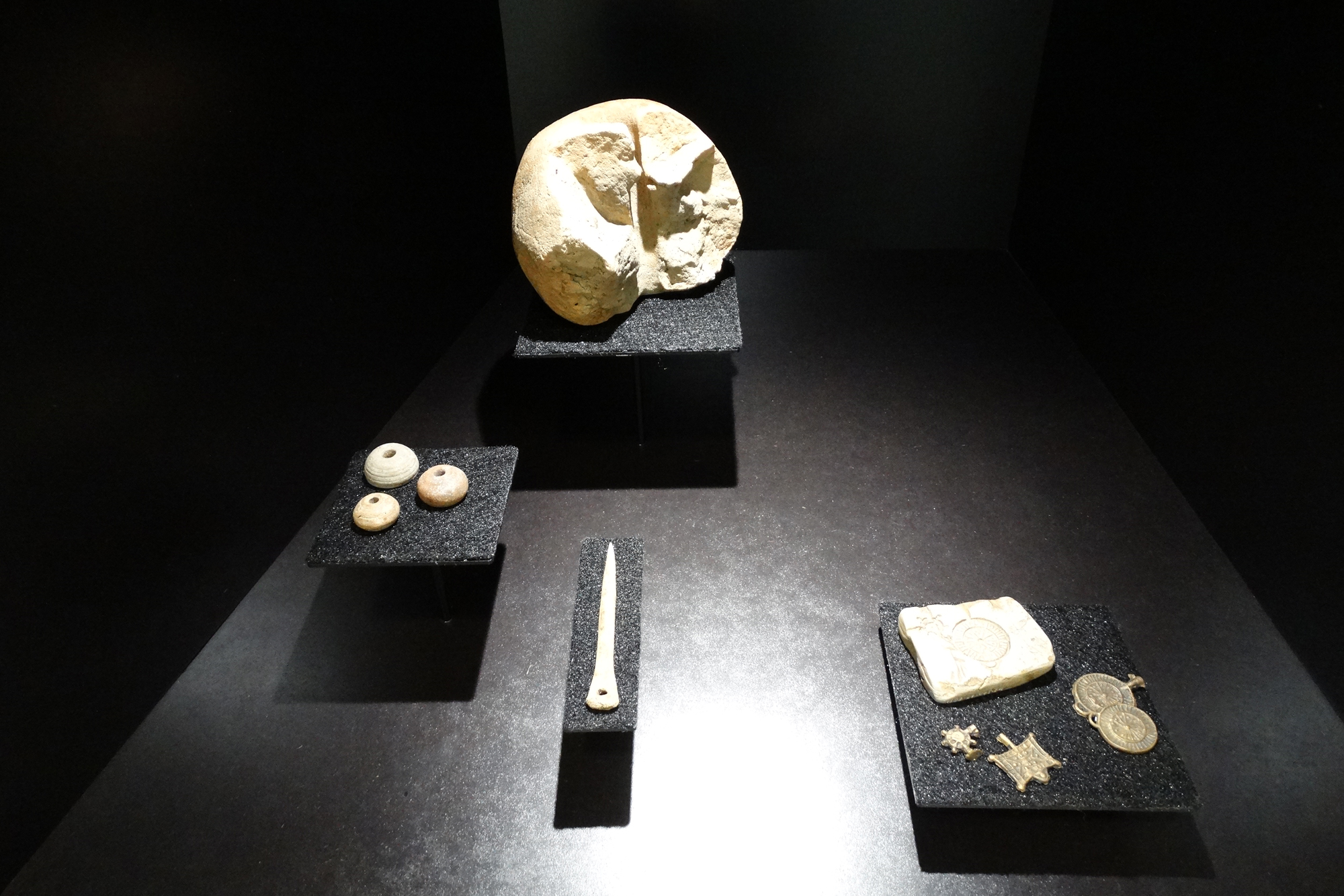 Blick in die Vitrine "Handel, Handwerk, Stadtgesellschaft": Spinnwirtel, Nähnadel, zerbrochenes Webgewicht und Gussform Spinnwirtel, Nähnadel, zerbrochenes Webgewicht und Gussform