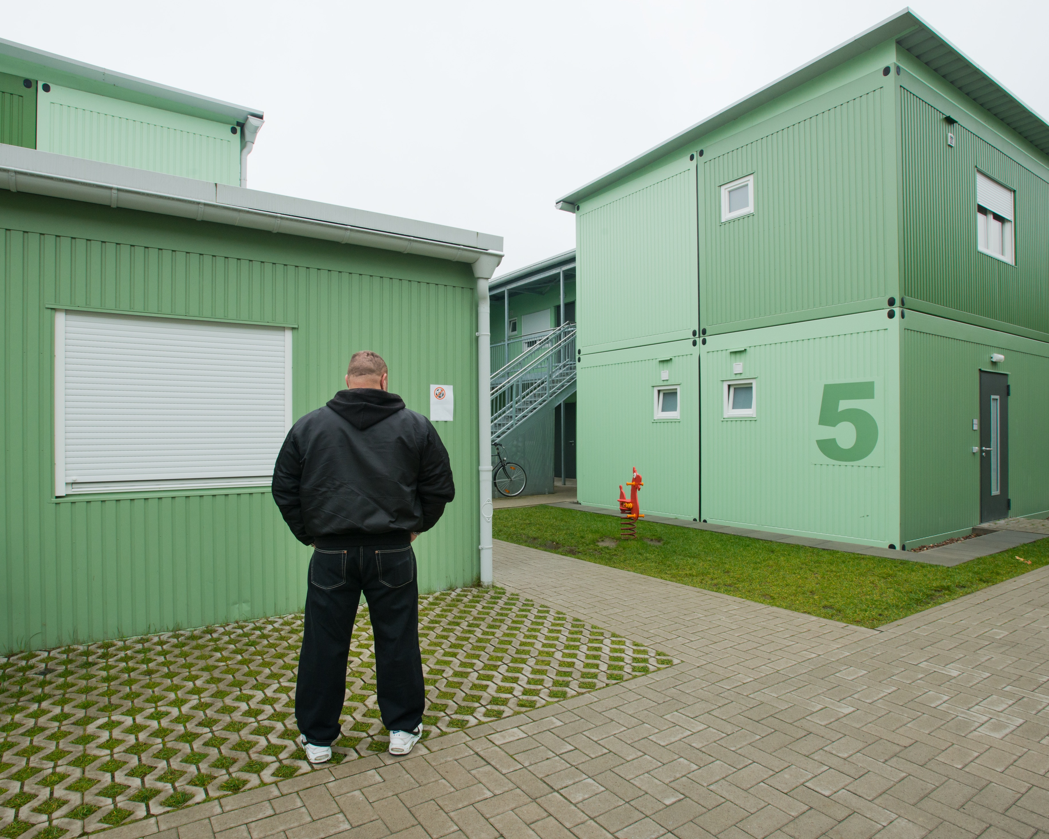Murat, ehemaliger Gefangener, von hinten, in einem Containerdorf. (c) Debi Cornwall Murat, ehemaliger Gefangener, von hinten, in einem Containerdorf. (c) Debi Cornwall