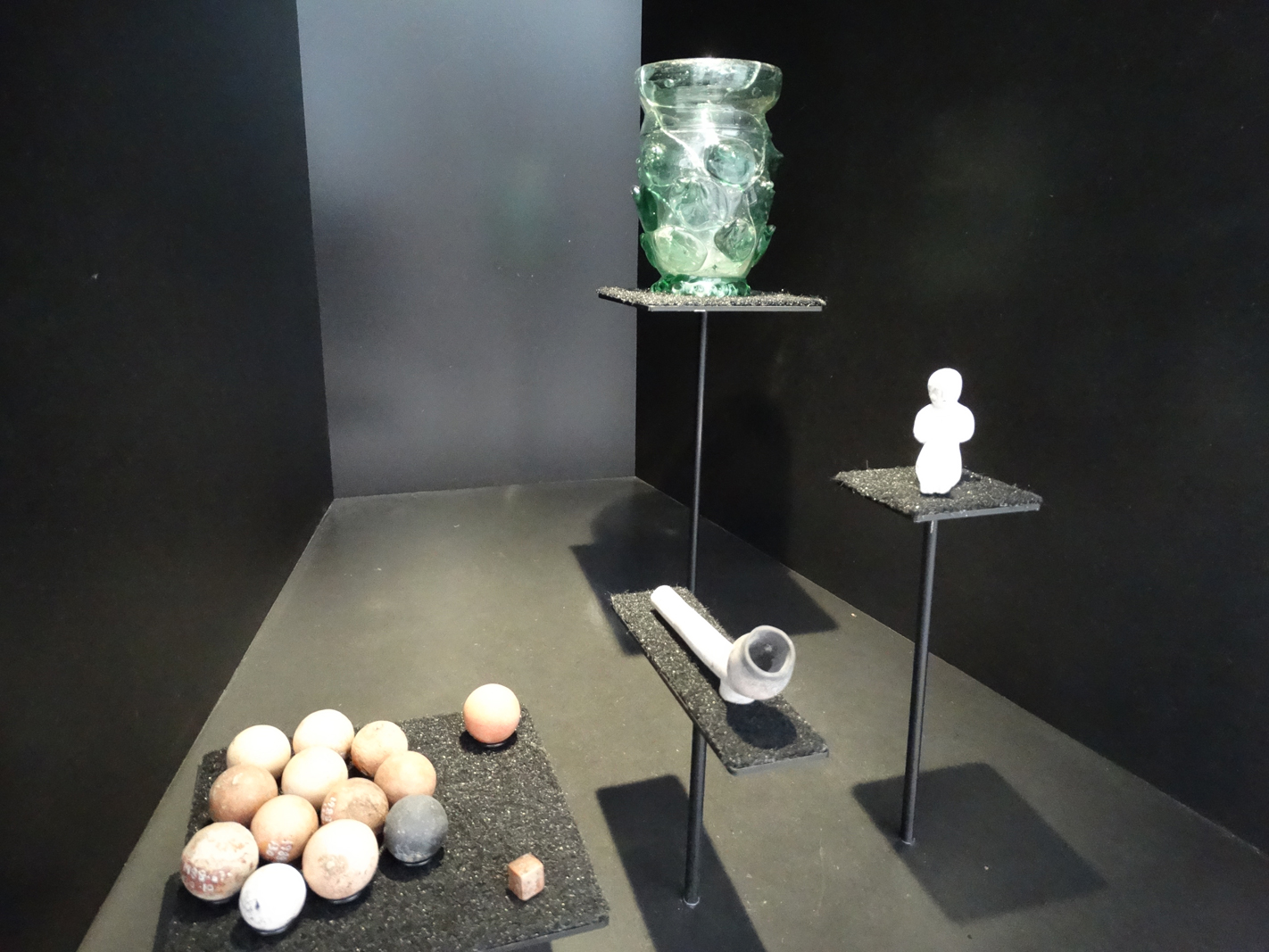 Vitrine 5: "Alltag und Fest". Mit Murmeln, einem Würfel, Tabakspfeife, einem Püppchen und "Krautstrunk". Foto: SP/Stadthaus Blick in die Vitrine zum Vitrine 5: "Alltag und Fest". Mit Murmeln, einem Würfel, Tabakspfeife, einem Püppchen und "Krautstrunk", einem verzierten, grünen Glasbecher. Foto: SP/Stadthaus